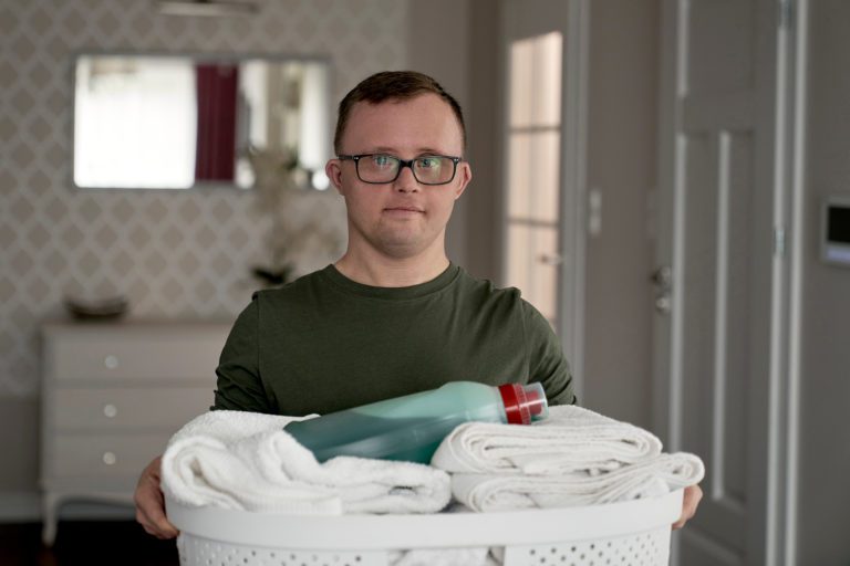 Person carrying laundry basket indoors.